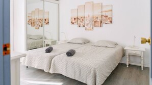 Ein Schlafzimmer mit einem Bett, zwei Nachttischen, einem Spiegel und einem Stadtbild an der Wand.