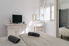 Ein Schlafzimmer mit zwei Betten, einem Schreibtisch, einem Fernseher und einem Spiegel.