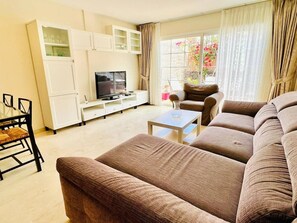 A living room with a sofa set, a television, a coffee table, and a dining area with a table and chairs.