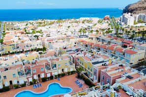 A coastal residential area with a swimming pool and sun loungers.