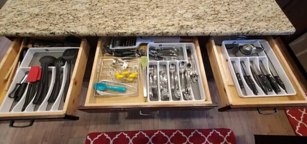 Un cajón de cocina con utensilios organizados en compartimentos.