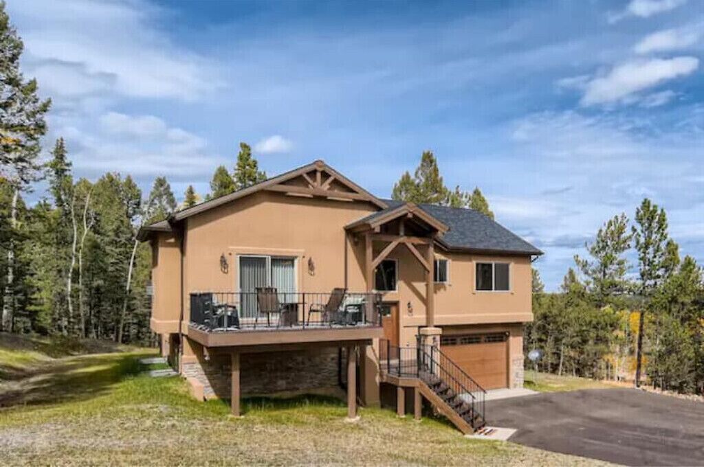 A two-story house with a balcony, a garage, and a stone foundation.