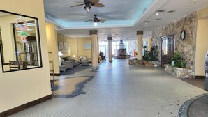 A hotel lobby with a large mirror, ceiling fans, and a patterned floor. - Beachfront Deluxe studio- Ocean Views! (Daytona Beach)