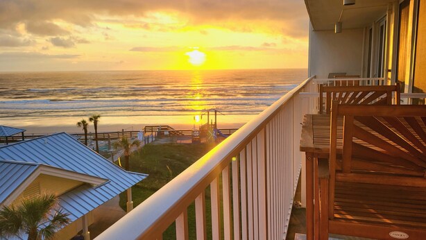 A balcony with a view of the ocean at sunset. - Beachfront Deluxe studio- Ocean Views! (Daytona Beach)
