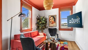 Una sala de estar moderna con un sofá rojo, un sillón negro, un tapete colorido y un ventanal con vistas.