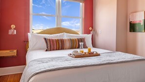 Una habitación de hotel con una cama grande, una bandeja de desayuno y una ventana con vistas al cielo.