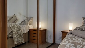 Une chambre à coucher comprenant un lit, une table de chevet, une commode et un grand miroir.