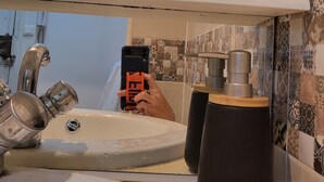 Une salle de bain avec un lavabo, un miroir et une étagère ornée d’objets décoratifs.