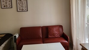 Une pièce avec un canapé en cuir rouge, une table blanche et deux œuvres d’art encadrées accrochées au mur.