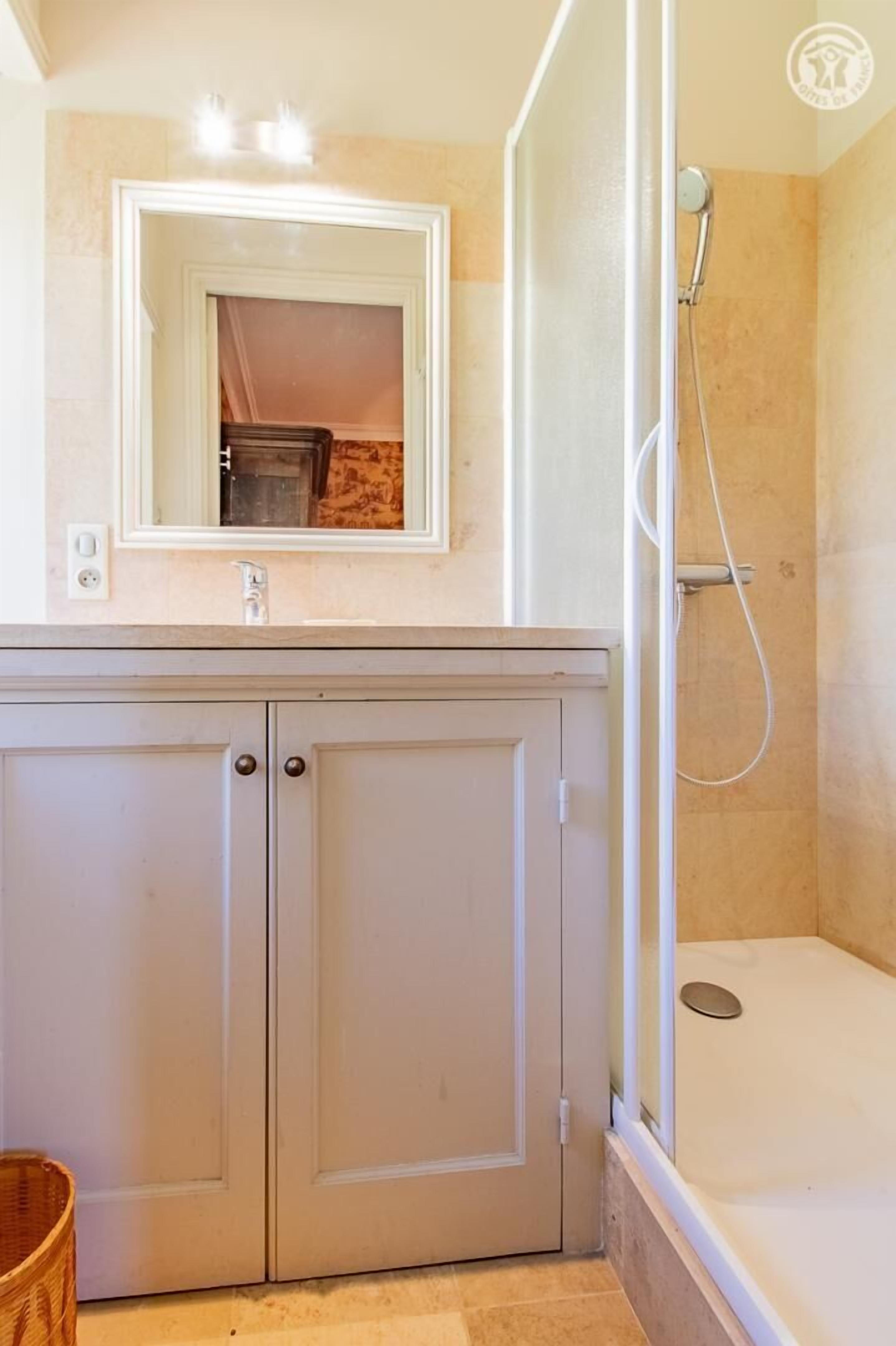 A bathroom with a shower, a sink with a mirror, and a cabinet.