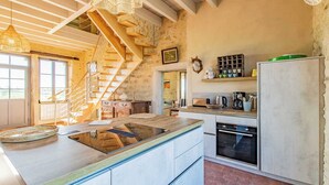 A kitchen with a central island, wooden staircase, and rustic decor. - la Corbière - Martigny-le-comte (MARTIGNY-LE-COMTE)
