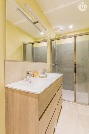Bathroom features a dual sink vanity, large mirror, and glass shower enclosure.