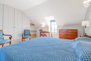Relax in this spacious room with a large bed, wooden wardrobe, and comfortable chair.