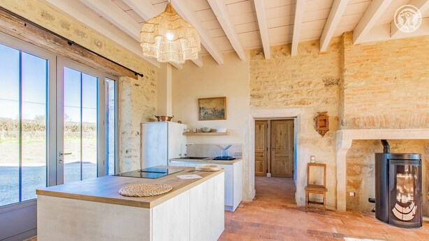A spacious kitchen with a large island, a stone wall, and a fireplace. - la Corbière - Martigny-le-comte (MARTIGNY-LE-COMTE)