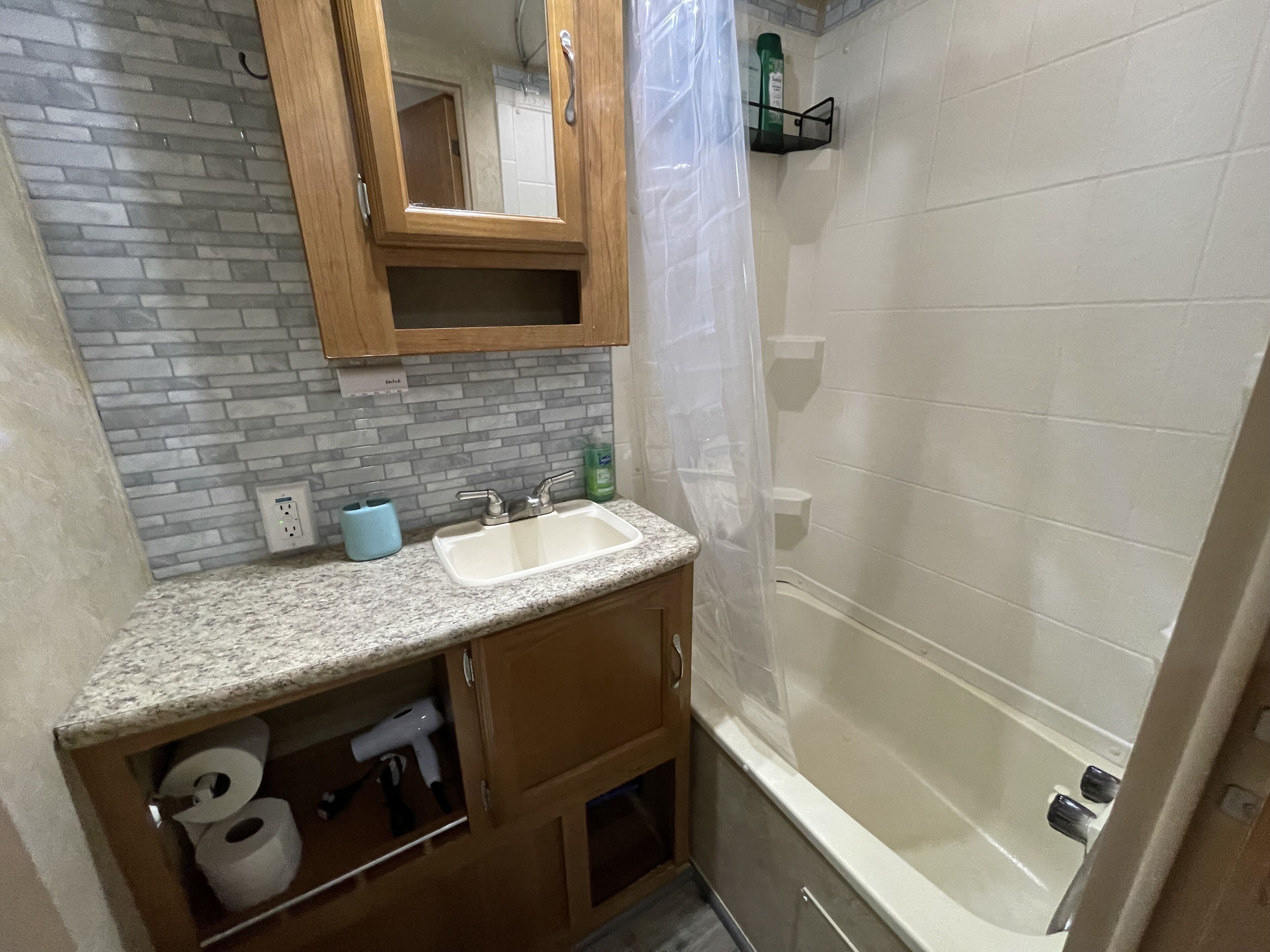 Une salle de bain avec un comptoir en granit, un lavabo, un miroir, une douche et des toilettes.