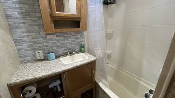 Une salle de bain avec un comptoir en granit, un lavabo, un miroir, une douche et des toilettes.