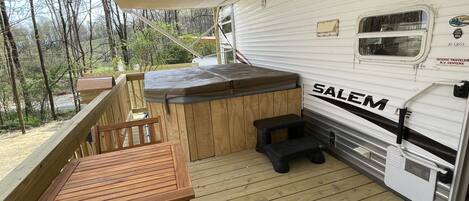 A covered deck with a wooden table and bench, a hot tub, and a white RV with "SALEM" branding.