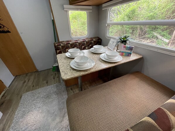 Uma cozinha compacta com bancada, uma janela com vista para o verde e um banco com jogo de mesa.