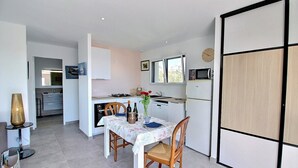 Une cuisine de taille réduite comprenant une table à manger, des chaises et un four à micro-ondes.