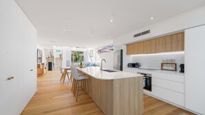Une cuisine moderne dotée d’un îlot central, de meubles en bois et d’un four encastré.