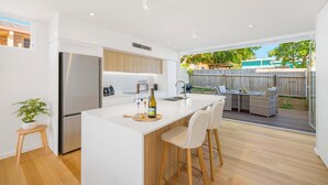 Une cuisine moderne dotée d’un îlot central, d’appareils électroménagers en acier inoxydable et offrant une vue sur le patio situé à l  ’arrière de la maison.