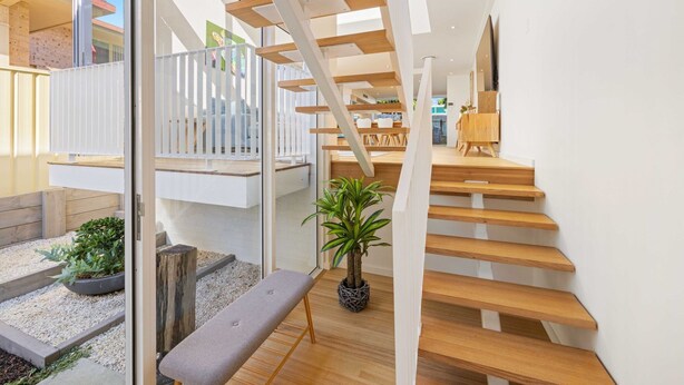 Un intérieur moderne avec un escalier en bois, un banc et une plante en pot.