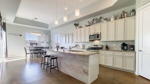 A spacious kitchen with a central island, white cabinetry, and modern appliances.