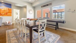 A dining area with a wooden table, white chairs, and a patterned rug.