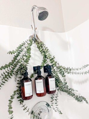 Ein Badezimmer mit Dusche, drei Duschgels und einer Pumpspenderflasche.