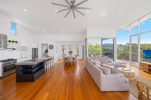 Relax in this open-plan living space with a kitchen and seating area, featuring a range, oven, and island with bar stools.