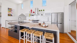 Une cuisine moderne dotée d’un îlot central, d’appareils électroménagers en acier inoxydable et d’un coin bar avec des tabourets.