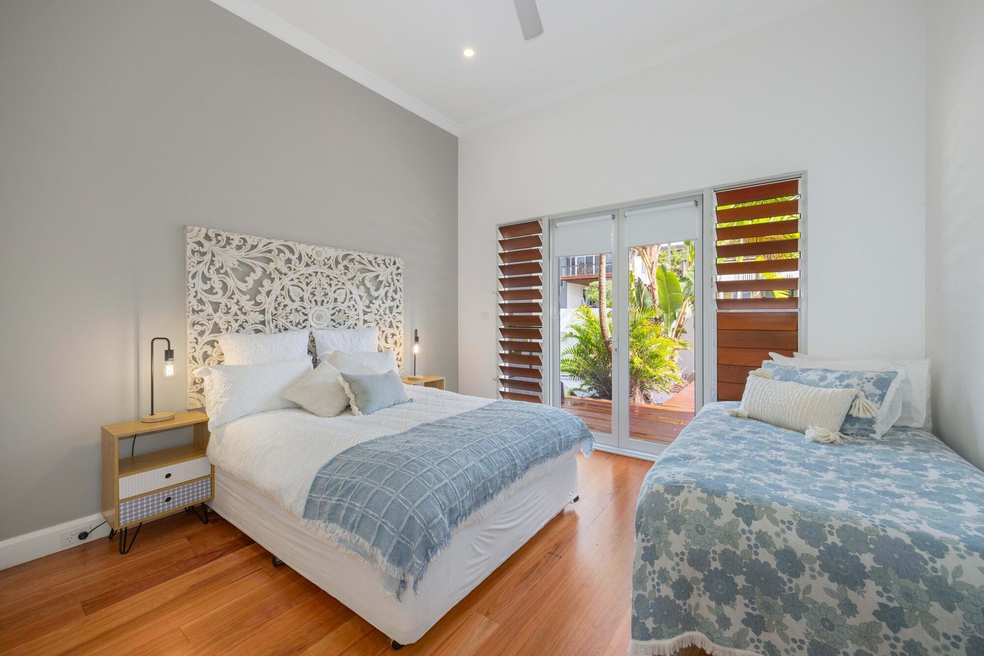 A bedroom with a large bed, a smaller bed, a nightstand, and a decorative headboard.