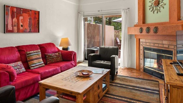 A living room with a red sofa, a wooden coffee table, a fireplace, and a painting on the wall.
