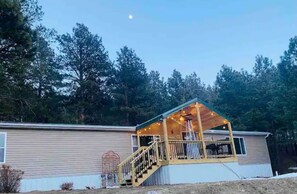A single-story mobile home with a covered porch and a staircase leading to the entrance. - Ridge Trail Lodge (Sturgis)