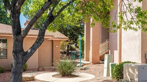 Un bâtiment avec un arbre au premier plan, un chemin et un petit espace aménagé en jardin.