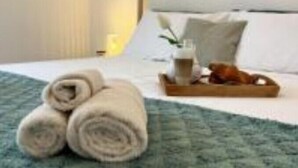 A neatly made bed with rolled towels, a tray with a cup and a book, and a white pillow on a blue textured bedspread. - Villa Radalj (Makarska)