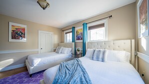 Un dormitorio con dos camas, una ventana con cortinas y una lámpara fijada a la pared.