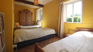 Une chambre avec deux lits, une armoire en bois, une fenêtre avec des rideaux et un luminaire suspendu.