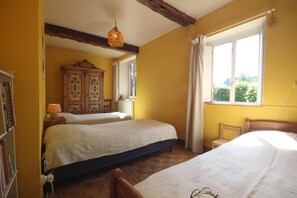 A room with two beds, a wooden cabinet, a window with curtains, and a hanging light fixture. - L'arbalète - ST Maclou DE Folleville (ST MACLOU DE FOLLEVILLE)