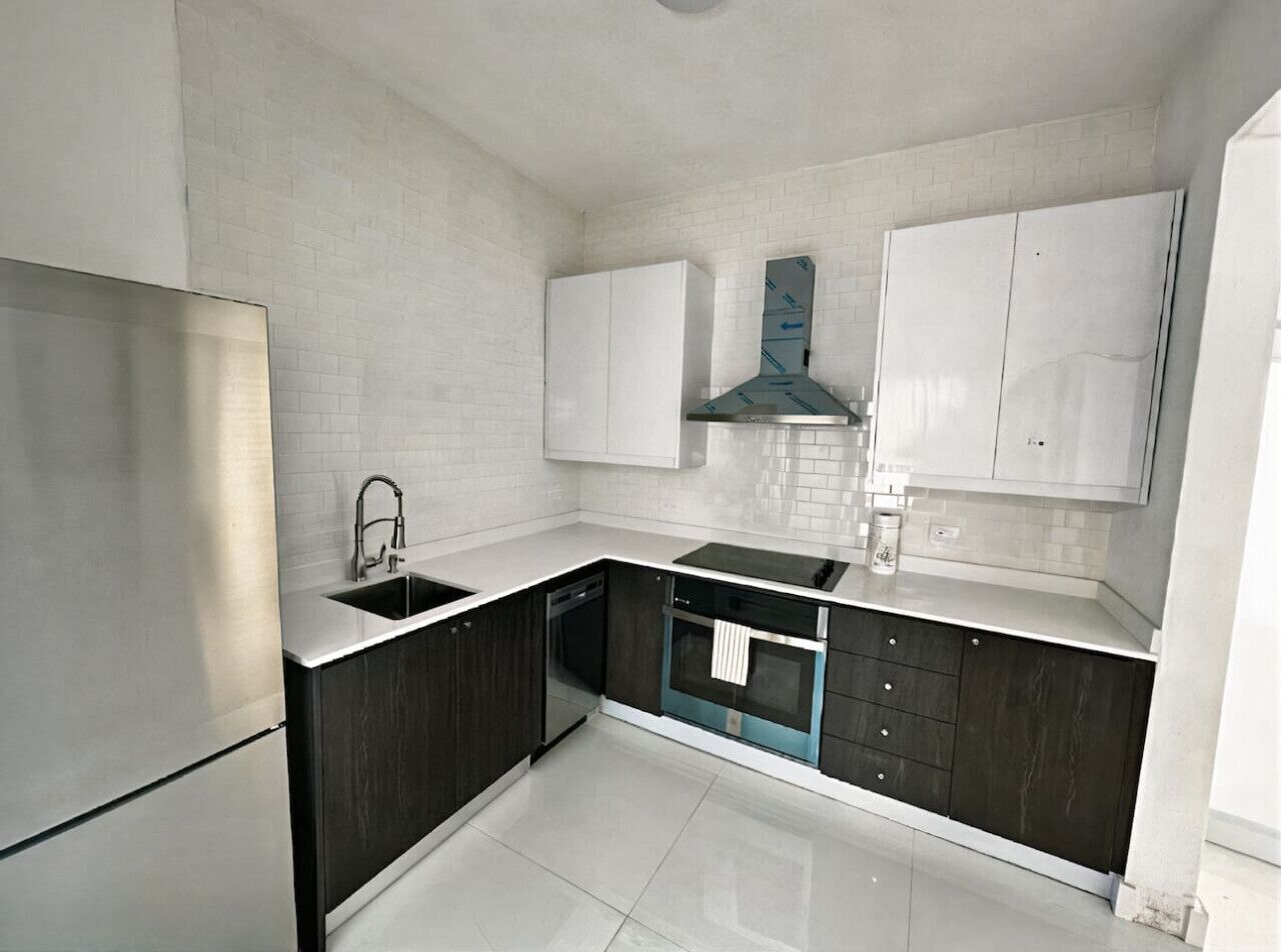 Una cocina moderna con armarios blancos, un refrigerador de acero inoxidable, lavavajillas y horno empotrado.