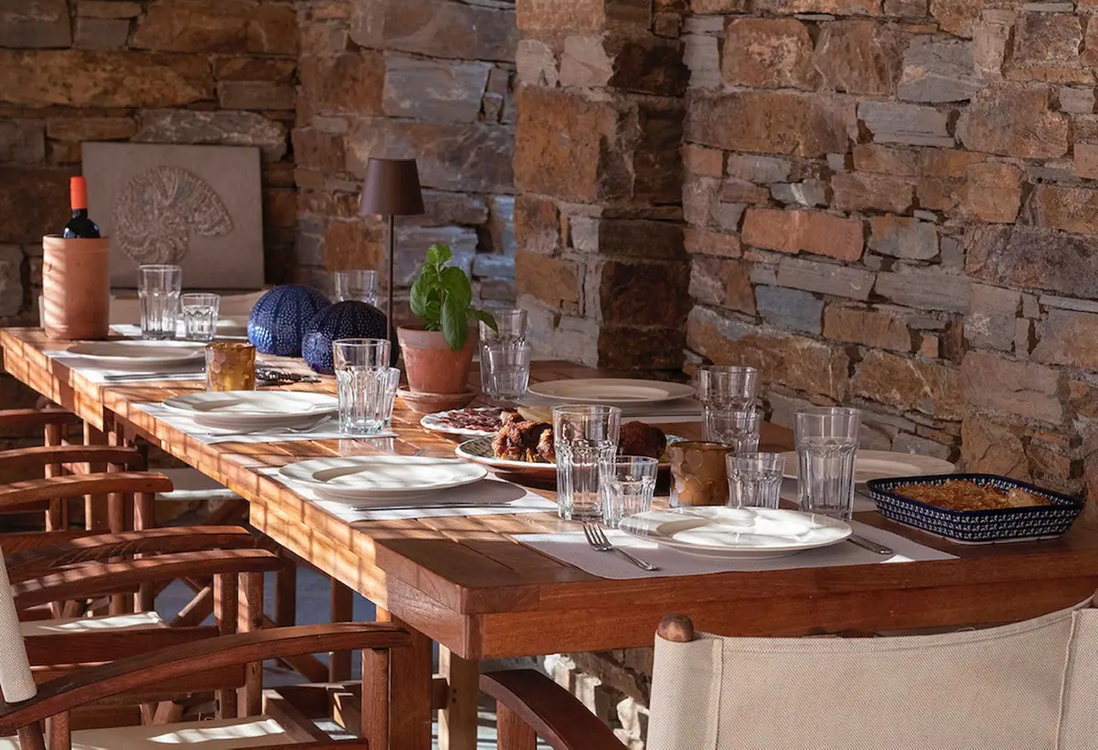 A long wooden dining table set with plates, glasses, and a centerpiece.