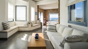 Uma sala de estar moderna com um sofá seccional, uma mesa de centro e vista para o oceano.