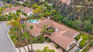 A residential property with a swimming pool, surrounded by palm trees and a well-maintained lawn. - Casa Azul (Poway)