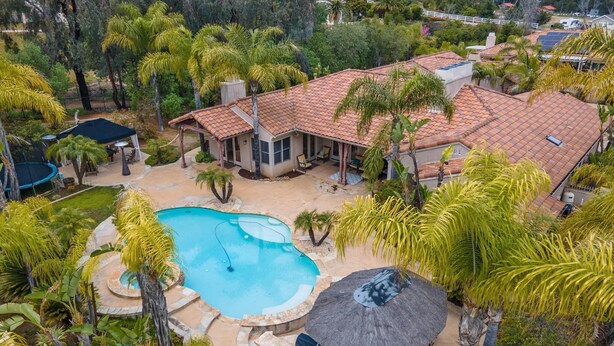 A residential property with a swimming pool, patio area, and a covered seating area. - Casa Azul (Poway)