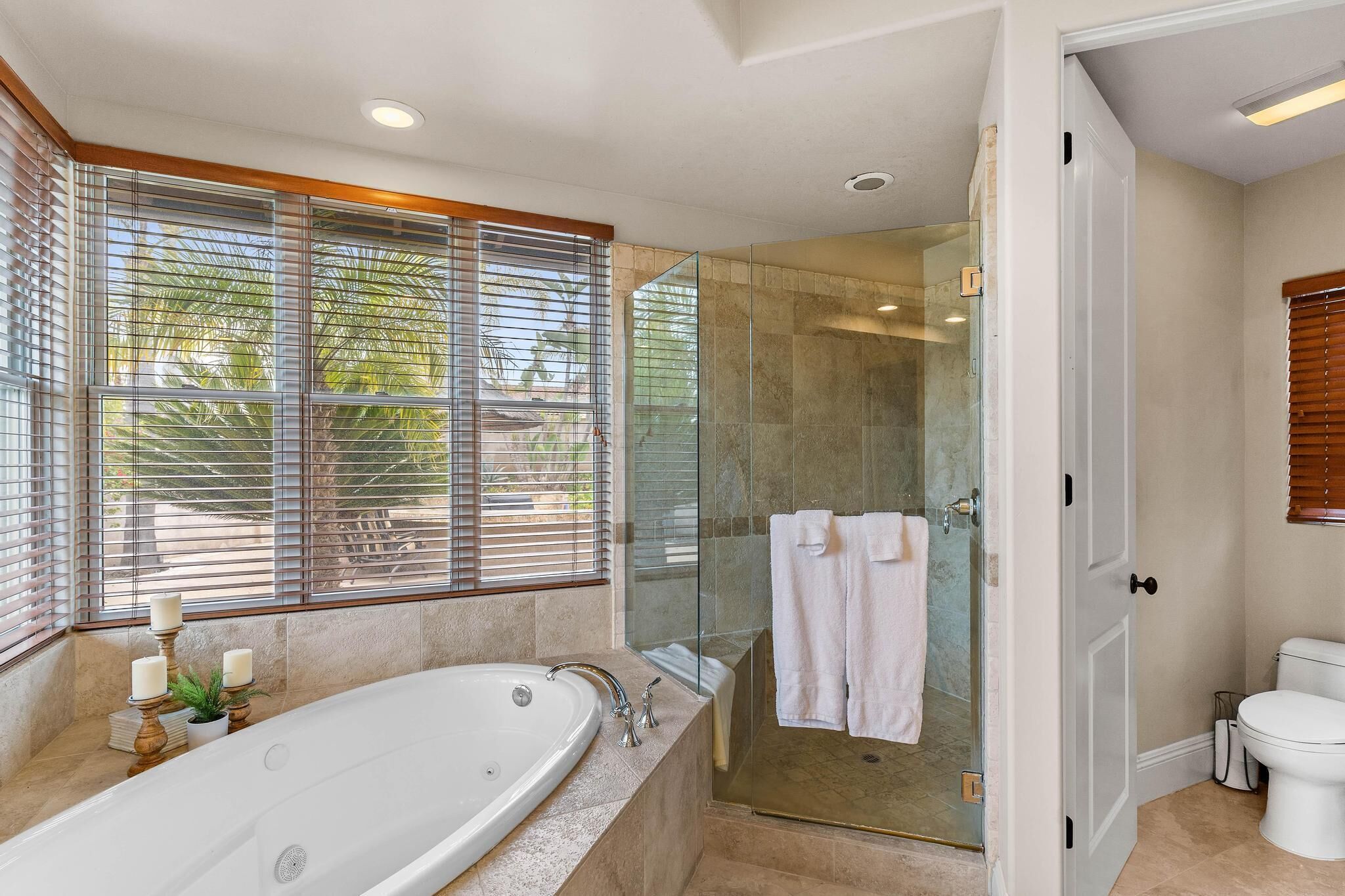 A modern bathroom with a glass-enclosed shower, a freestanding bathtub, and a toilet.