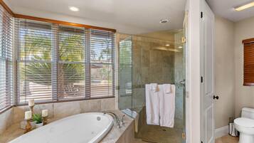 A modern bathroom with a glass-enclosed shower, a freestanding bathtub, and a toilet.