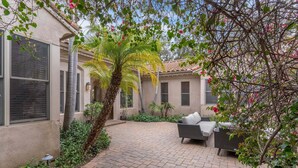 A patio area with a brick floor, a palm tree, and outdoor furniture. - Casa Azul (Poway)