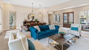 A spacious living room with a blue sofa, white armchairs, and a wooden coffee table. - Casa Azul (Poway)