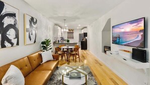 A modern living room with a sofa, coffee table, and a TV displaying a sunset scene.