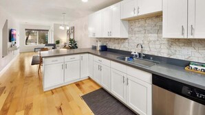 A modern kitchen with white cabinets, a marble backsplash, and a stainless steel dishwasher.